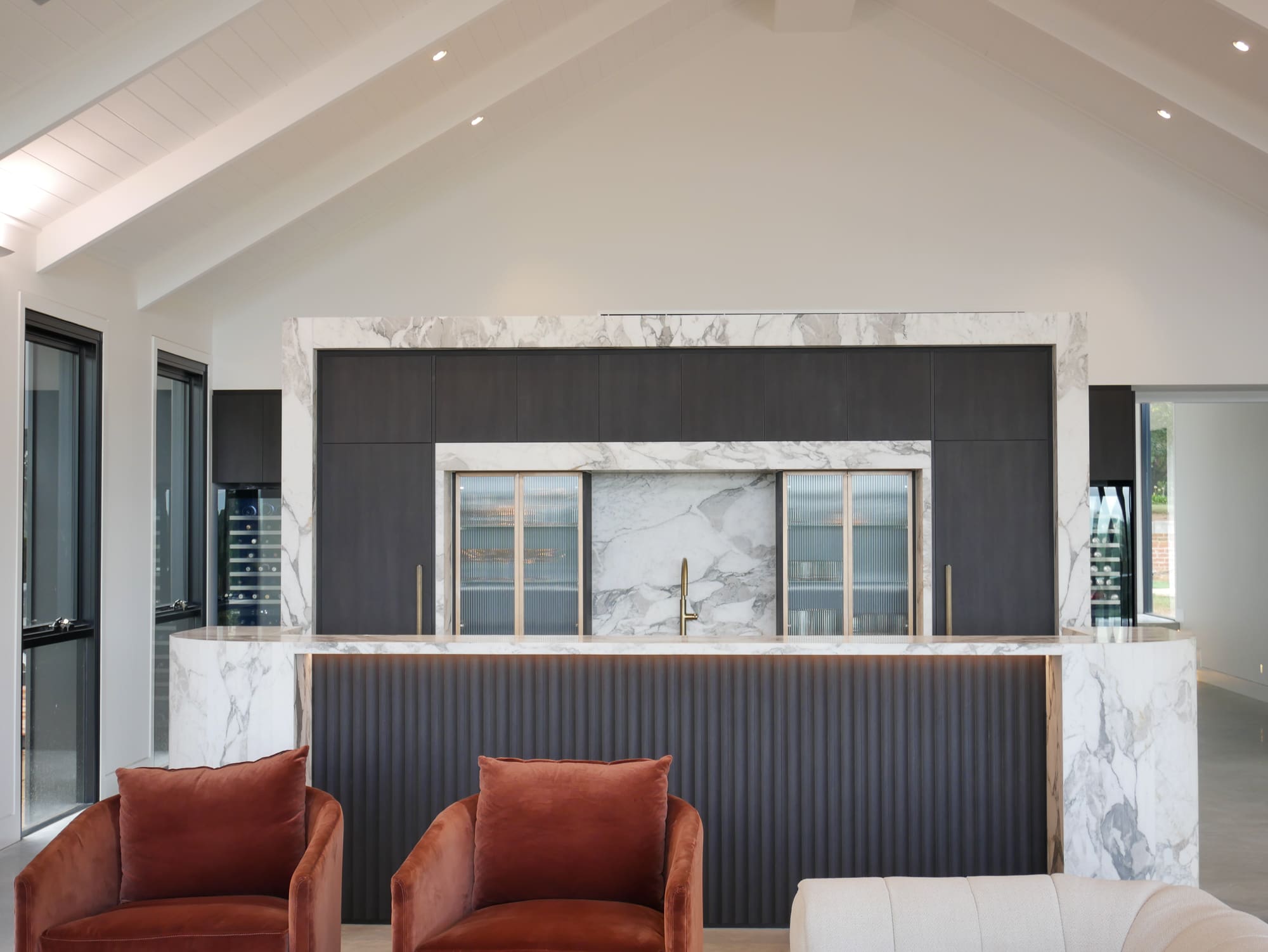 stone curved kitchen island bench with fluted panels in between the curves. 