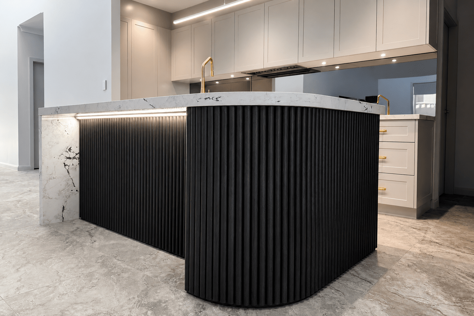 Modern kitchen featuring a curved fluted timber kitchen island in black woodgrain with LED lighting, marble benchtops, shaker cabinetry and brushed gold tapware in a luxury contemporary home.