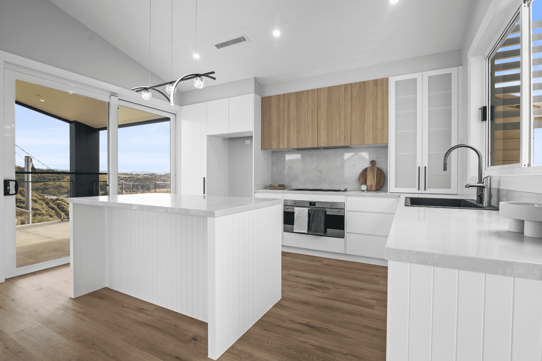 kitchen island with panel cladding, stone benchtop and timber upper cabinets. 
