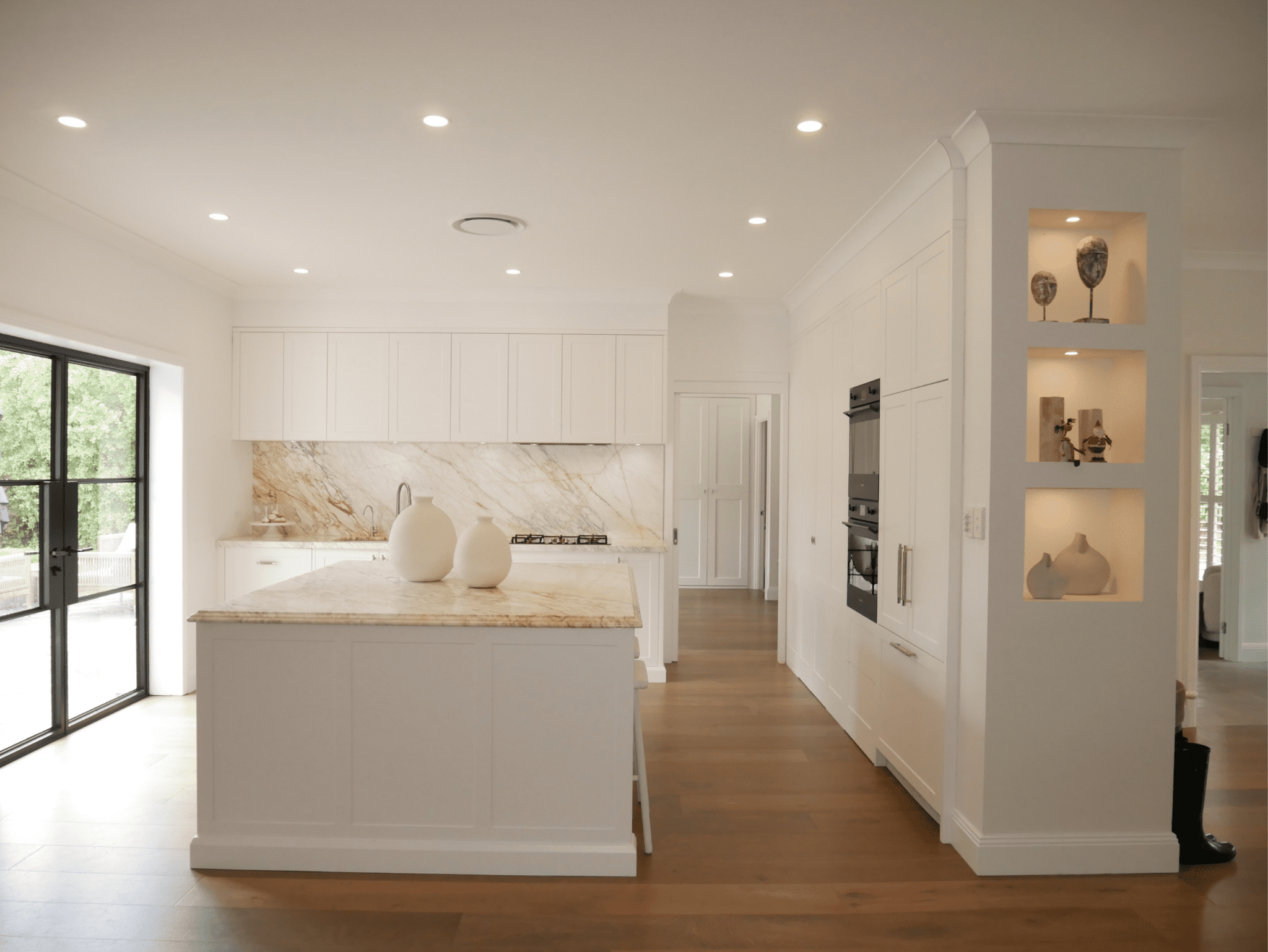 After the complete kitchen rebuild: a bright white shaker-style kitchen featuring Calacatta marble benchtops, integrated appliances and newly opened walls for a modern, spacious feel.