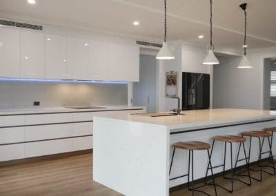 Modern white perfection kitchen Razorback with white stone waterfall benchtops and three handing pendant lights