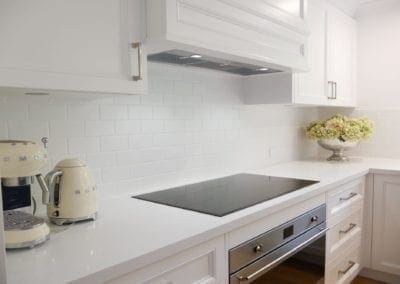tranquil two toned family kitchen bowral cooktop with white subway tiles splashback