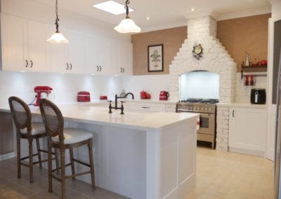 Character country filled kitchen in Mittagong white cabinetry with red appliances