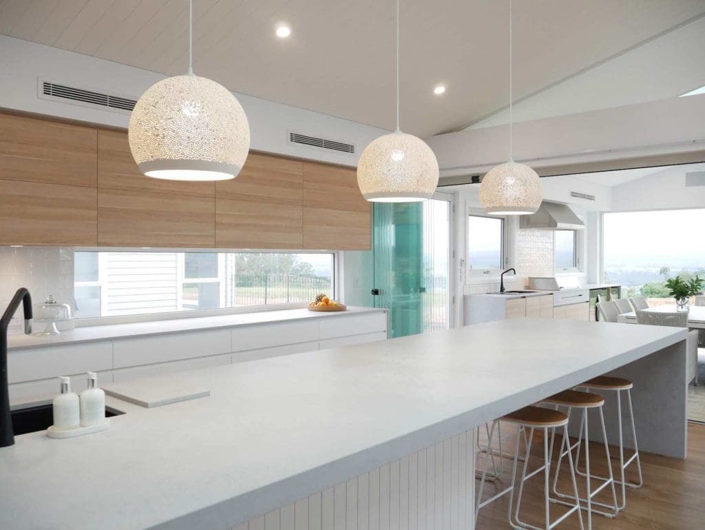 Modern kitchen with 20mm and 60mm Caesarstone Airy Concrete benchtops, statement waterfall island dining table, and pendant lighting.