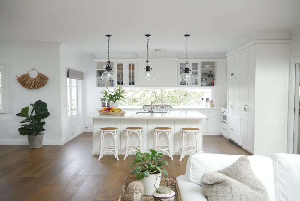 Hamptons style kitchen with white cabinetry, pendant lighting, and timber flooring