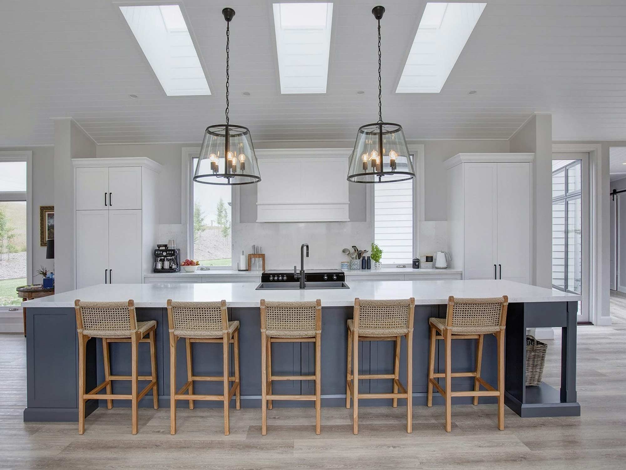 Stylish-Country-Hamptons-Kitchen-Moss-Vale-wall-cabinetry Hamptons Style Kitchen featuring coloured island with two large black pendant lights and white cabinetry.