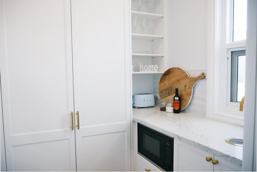 Stylish butler's pantry with white cabinetry, marble benchtop, and modern appliances