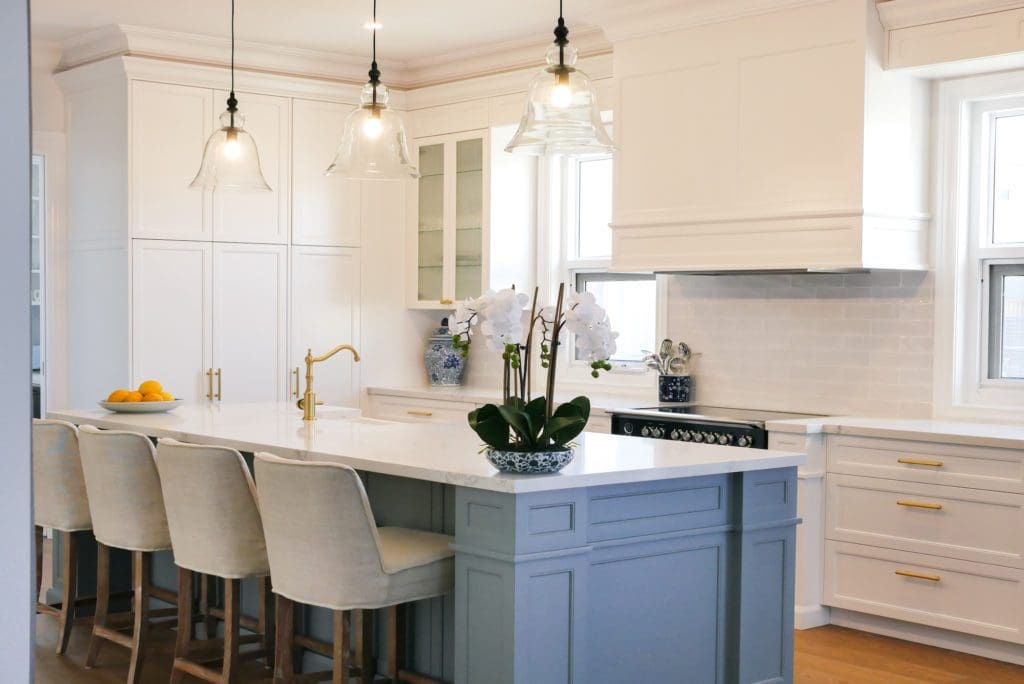 Hamptons style kitchen with shaker cabinets, pendant lights, and a blue island bench
