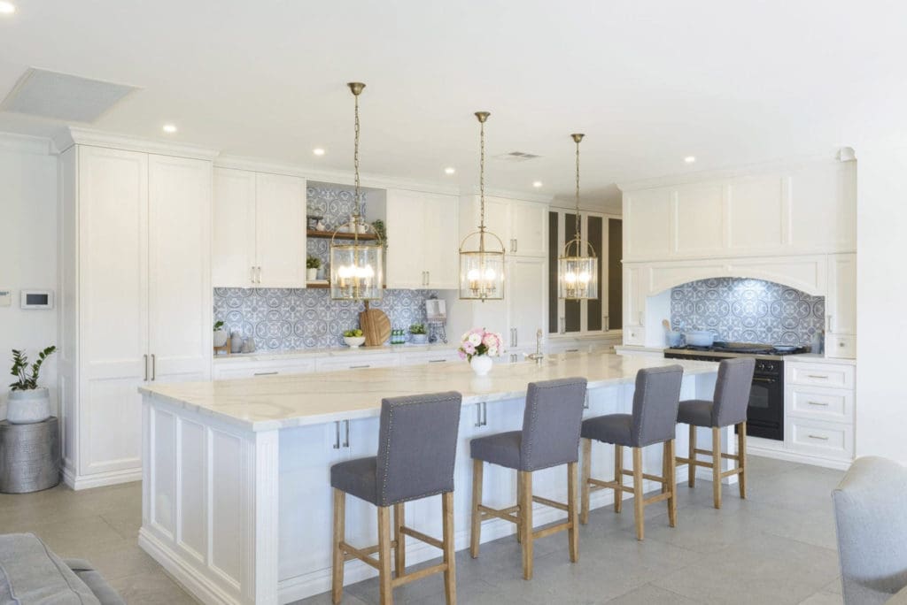 Spacious luxury kitchen with a large island bench, pendant lighting, and upholstered bar stools.