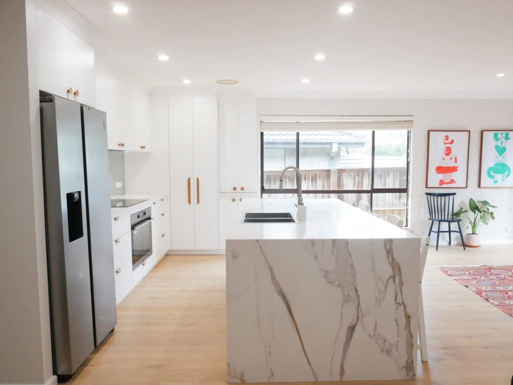 Bright modern white kitchen with marble island and the best kitchen lighting highlighting clean lines and open space.