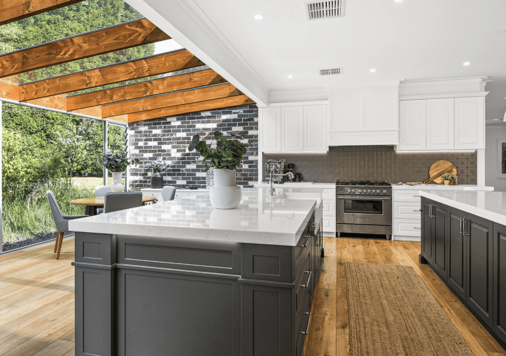 Kitchen with two islands: one featuring an overhang for seating and storage, and the other serving as a 'workbench' with a semi-integrated Siemens dishwasher, Chambord Louis butler’s sink, gooseneck tap, ample drawers, and a hidden double bin system.