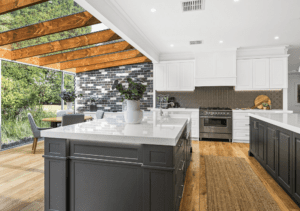 Kitchen with two islands: one featuring an overhang for seating and storage, and the other serving as a 'workbench' with a semi-integrated Siemens dishwasher, Chambord Louis butler’s sink, gooseneck tap, ample drawers, and a hidden double bin system.