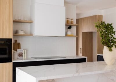 Dulux Lexicon quarter strength in a matte finish applied to all upper cabinetry, including the rangehood. Polytec Plantation Ash in a woodmatt finish adds timber accents with tall doors and shelving in both the kitchen and pantry.
