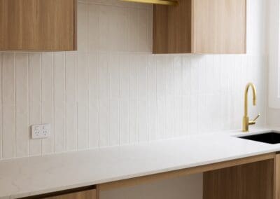 Polytec Plantation Ash in a woodmatt finish used for cabinetry in the laundry, complemented by ABI Interiors Elysian Commercial Pull-out Mixers.