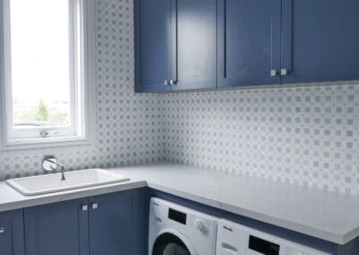 The laundry features colour-matched blue cabinetry with dark anthracite carcasses.