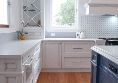 Natural light flows into the kitchen, highlighting the stunning medium antiqued hand-painted cabinetry, with Dulux Lexicon quarter strength over the rich Dulux Domino. The island is colour-matched to the blue of the client’s Falcon cooker.