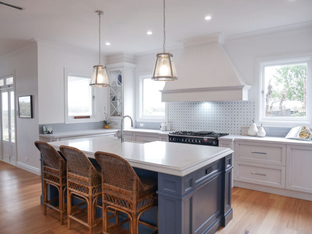 Natural light opens up the kitchen, illuminating the stunning medium antiqued hand-painted cabinetry, with Dulux Lexicon quarter strength over the rich Dulux Domino. The island is colour-matched to the blue of the client’s Falcon cooker.