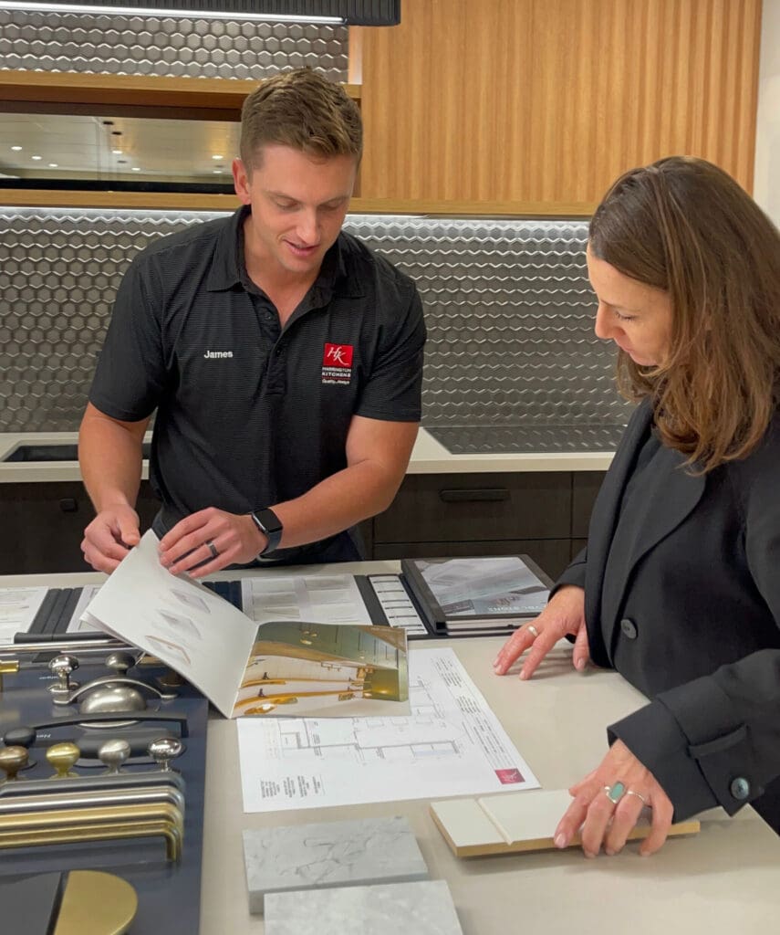 Kitchen designer consulting with client over layout plans, finishes, and handles during a Harrington Kitchens design appointment.