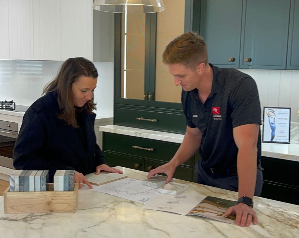 Kitchen designer and client reviewing samples and floor plans during collaborative design work at Harrington Kitchens.