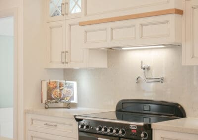 The Black Falcon freestanding oven pairs beautifully with the soft taupes and greys of Caesarstone Bianco Drift, featuring a pot filler is elegantly positioned beneath the decorative rangehood canopy.