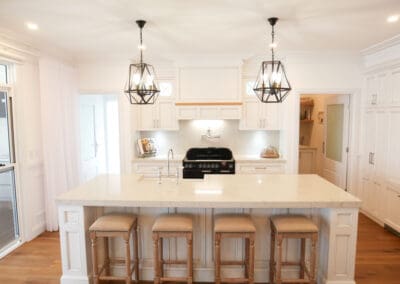 The kitchen’s elegance is highlighted by Caesarstone Bianco Drift with 40mm mitred edges and 60mm on the island. Bold black glass and metal pendants complete the look. Dulux Lexicon quarter strength and Dulux Domino create a striking contrast, while traditional profiles and proud island kicks add luxury. Hand-painted antique Kitchen Oak Flats finish the timeless design.