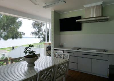 Modern alfresco kitchen featuring Polytec Alfresco Range in Boxed Brush Grey, paired with Caesarstone Midday outdoor stone benchtops with 40mm mitred edges. A matching stone splashback keeps the BBQ and cooking area clean and dirt-free.