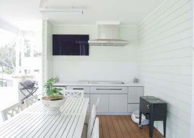 Modern alfresco kitchen with Polytec Alfresco Range in Boxed Brush Grey, complemented by Caesarstone Midday outdoor stone benchtops with 40mm mitred edges. The matching stone splashback ensures a clean, dirt-free BBQ and cooking area.