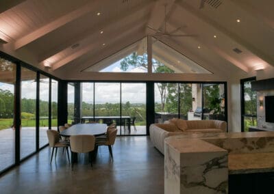 Luxury open-plan living and dining space with cathedral ceiling, marble kitchen island, and panoramic views in Cobbitty.