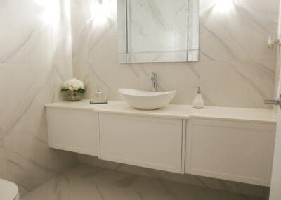 Ensuite and powder room vanities with top mount San Ceramica sinks, modern single taps, and 20mm Quantum Quartz Alpine White surfaces, matching the cabinetry throughout the home.