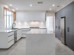 Modern kitchen featuring a sleek marble-look kitchen island with matte cabinetry and integrated appliances.
