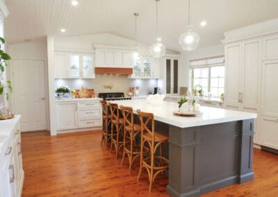 Elegant country-style kitchen with white cabinetry, timber flooring, and a large dark grey island bench.