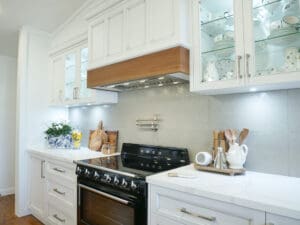Elegant country kitchen with a Smeg cooktop and bright Kitchen Under Counter Lights illuminating glass-front cabinets and a stone splashback.