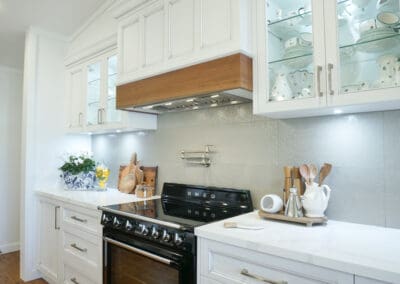 Elegant country kitchen with a Smeg cooktop and bright Kitchen Under Counter Lights illuminating glass-front cabinets and a stone splashback.