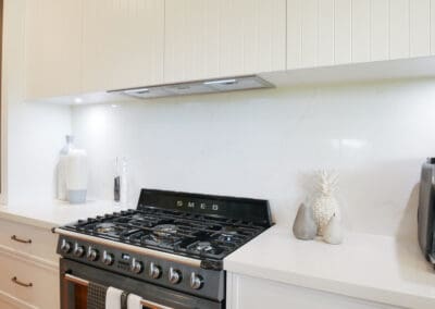 Modern Hamptons-style kitchen with a gas stove and Kitchen Under Counter Lights illuminating a white splashback.