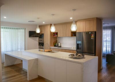 Contemporary two-toned kitchen featuring YDL Stone kitchen island bench, timber cabinetry, and modern pendant lighting.