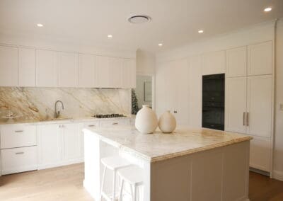 Classic white kitchen with Calacatta marble benchtops and splashback, shaker cabinetry, and a central island.