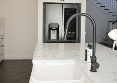 Fireclay butler sink with gooseneck tap and marble-look benchtop in a modern provincial kitchen.