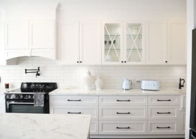 White provincial kitchen cabinets with cross-style glass doors and marble-look benchtop.