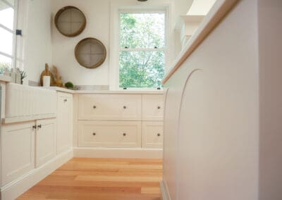 Country kitchen with shaker-style cabinetry, farmhouse sink, and natural light from a central window.