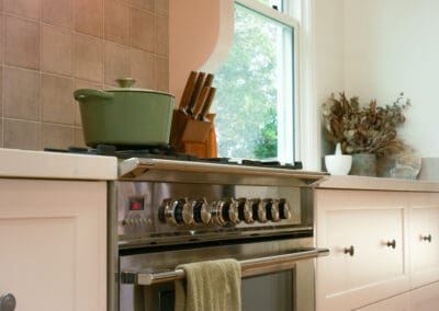 Country kitchen featuring a premium Fisher & Paykel oven set beneath a custom range hood and tiled splashback.