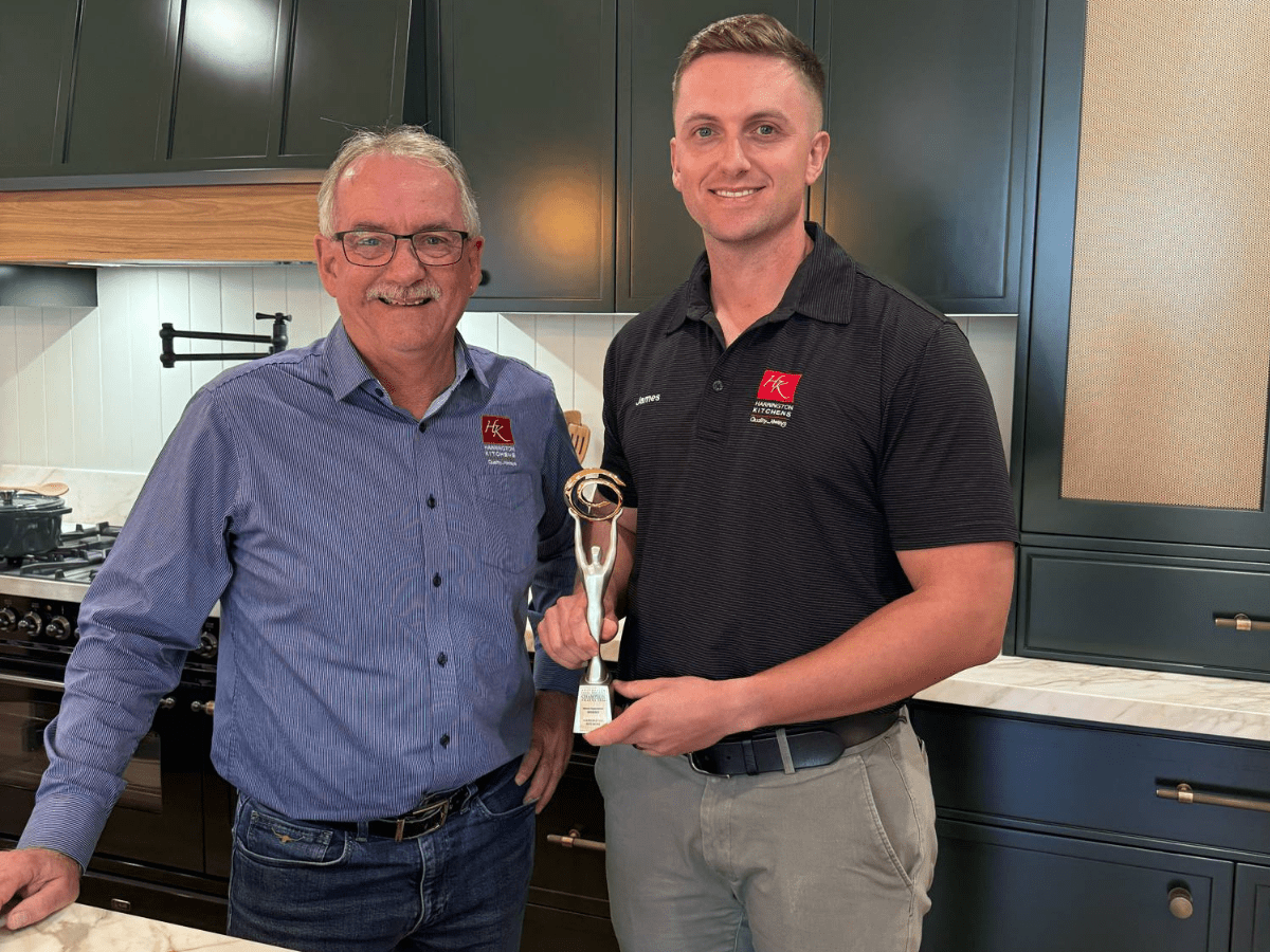 Mark and his son James smiling and holding the 2024 Small Business Awards trophy, celebrating their win for Harrington Kitchens.