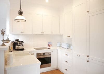 Stylish white kitchen with shaker cabinets, marble-look countertops, and pastel blue SMEG appliances.