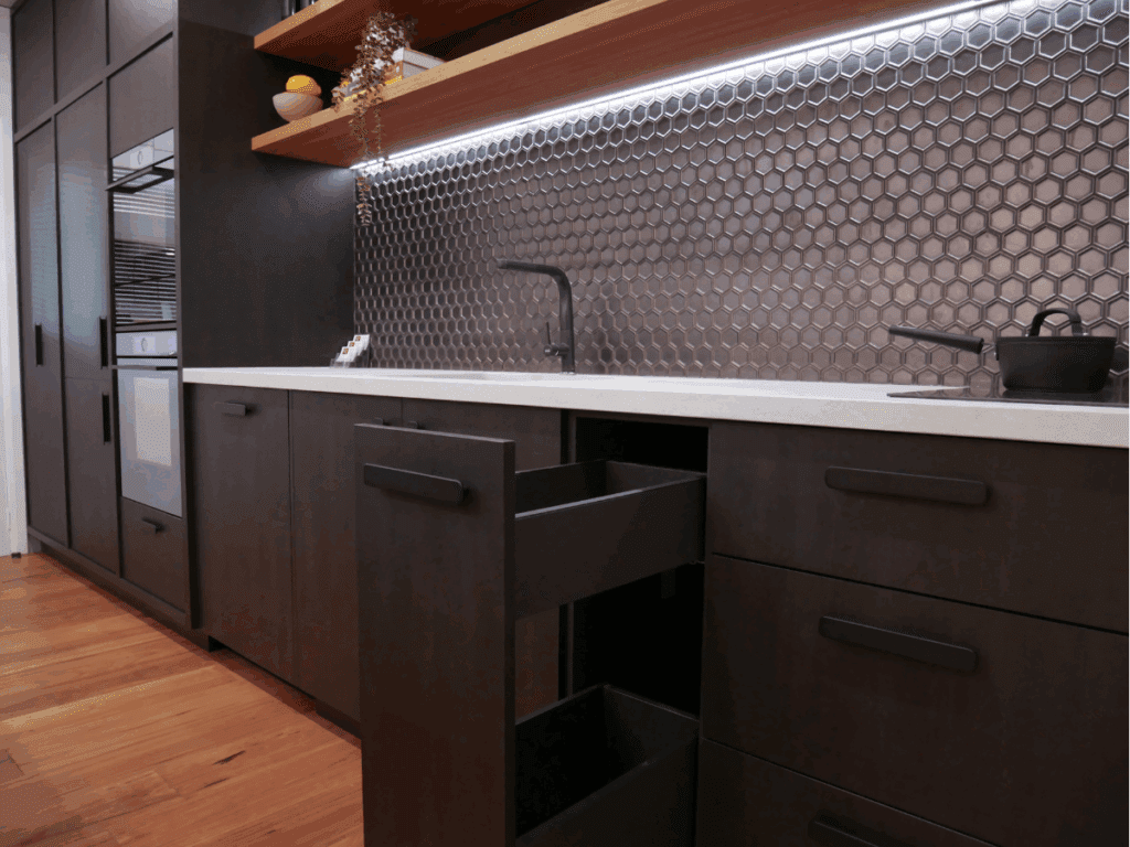 Modern dark-toned kitchen with sleek cabinetry, honeycomb tile splashback, and integrated storage, designed by a premium kitchen manufacturer in Sydney.