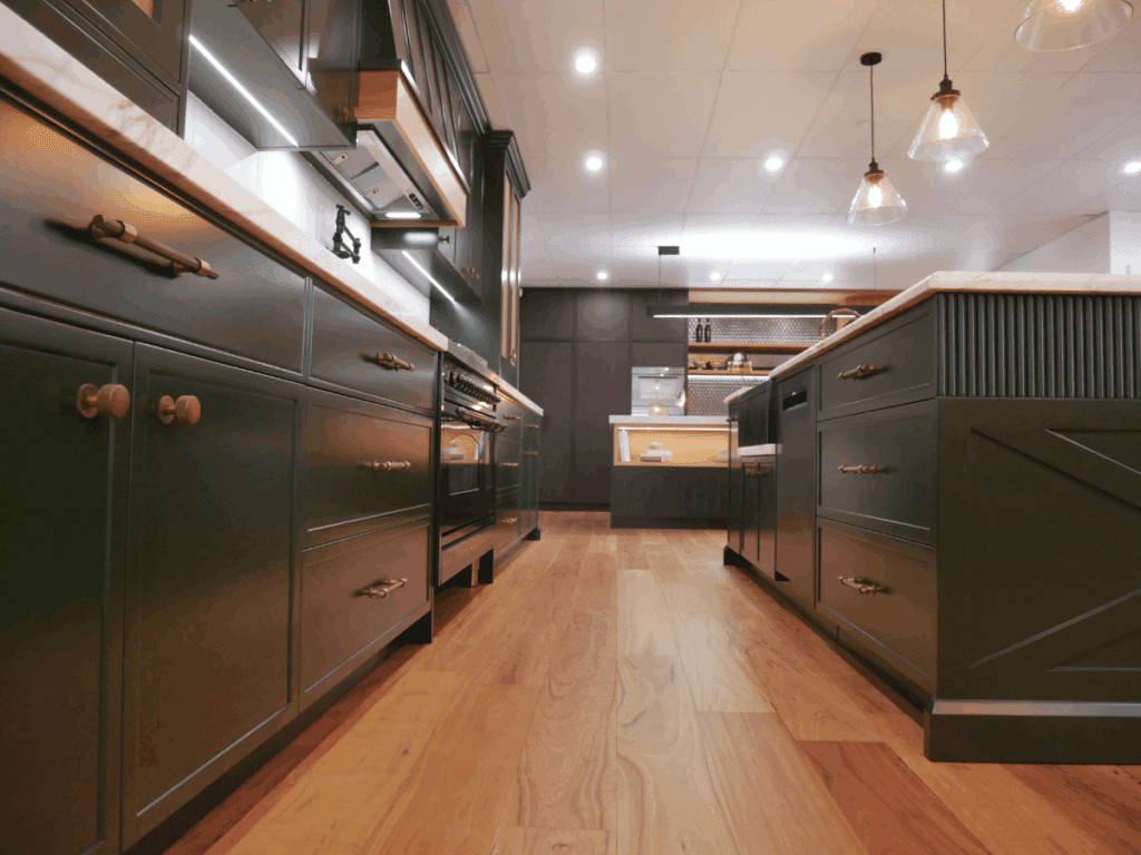 Luxury kitchen display featuring dark green cabinetry, marble benchtops, and modern pendant lighting, showcased by a leading kitchen manufacturer in Sydney at the Harrington Kitchens showroom in Narellan.