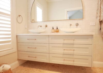 Hamptons-style bathroom vanity with shaker drawers, twin vessel basins, and brushed nickel hardware.