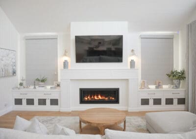 Elegant Hamptons-style living room with feature fireplace, shaker cabinetry, and wall-mounted TV.