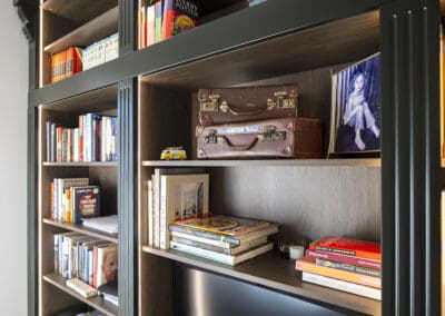 Home study with custom dark timber shelving, integrated desk, built-in lighting, and a neatly styled display of books and decorative pieces.