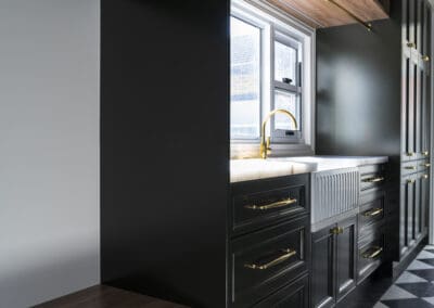 Mudroom with dark green cabinetry, gold hardware, timber accents, and checkerboard flooring.