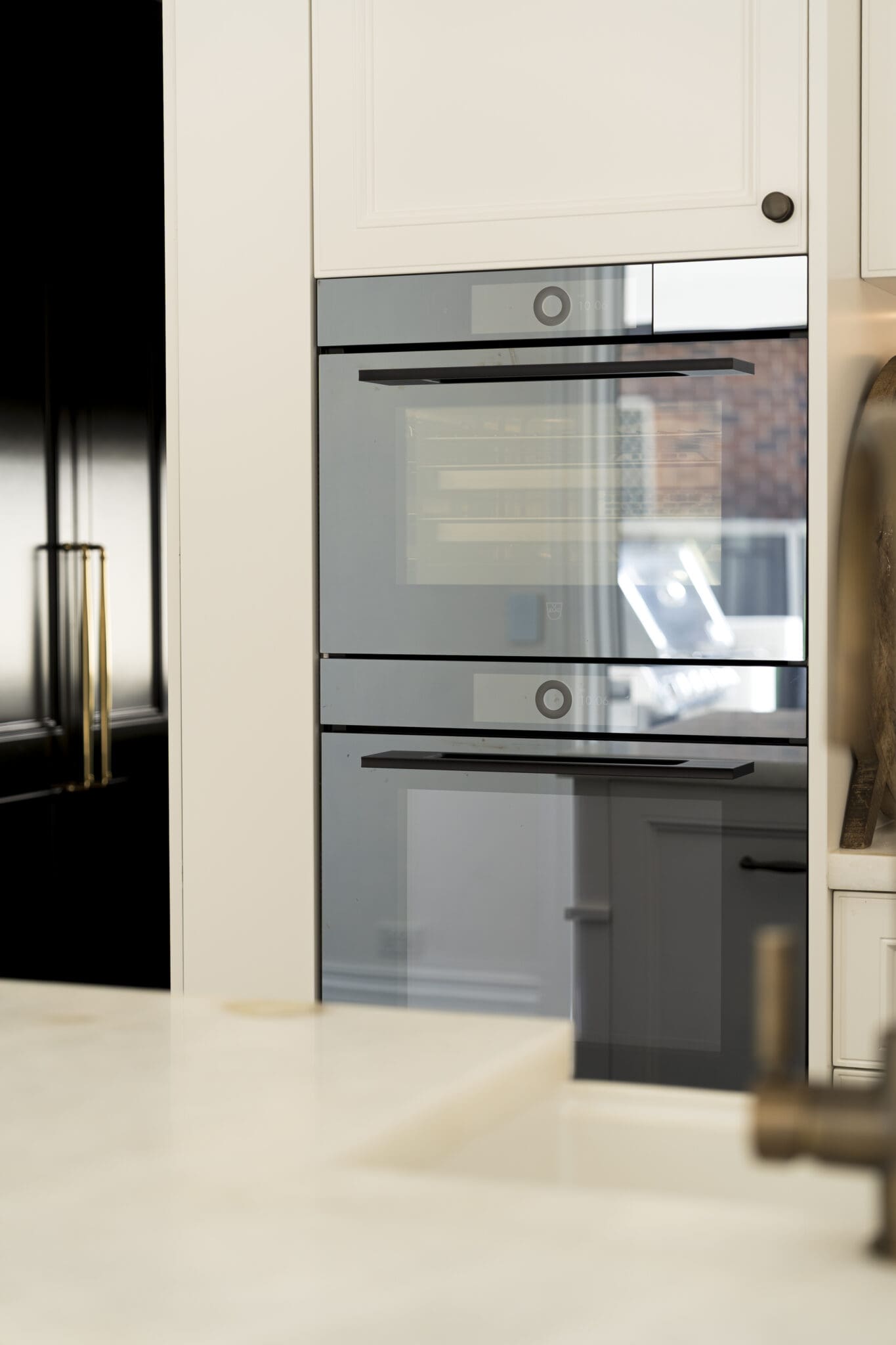 Built-in combi oven tower with sleek glass front, set within classic white cabinetry.