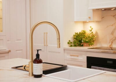 Bespoke white kitchen featuring a Franke Eos Neo gold pull-out tap.